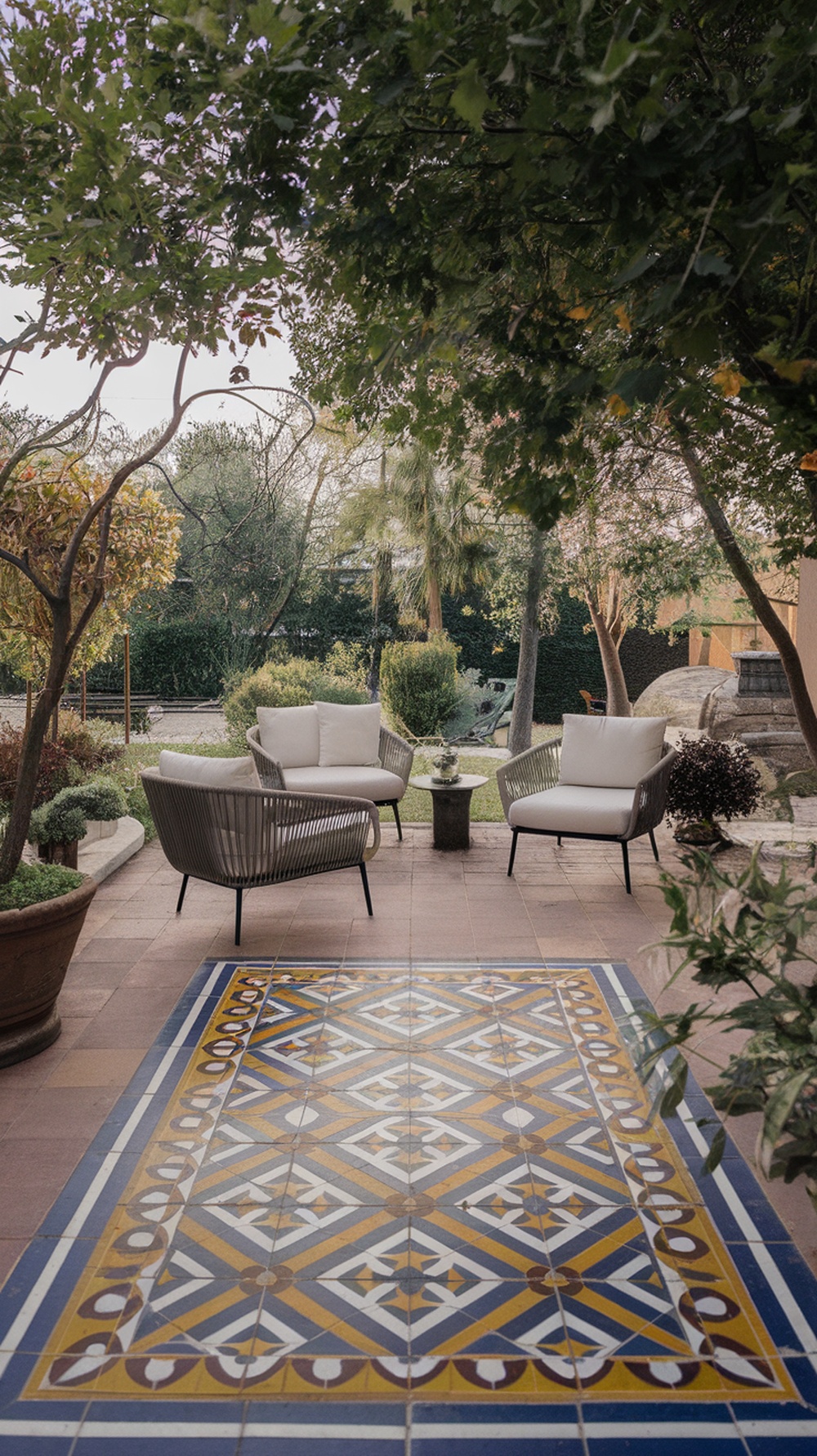 A beautifully designed patterned tile patio surrounded by greenery, featuring cozy seating and vibrant geometric patterns.