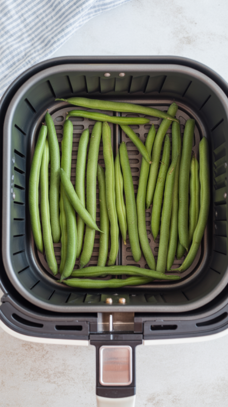 Air fryer basket showing green beans properly arranged in single layer